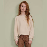Maglia beige lavorazione a treccia con maniche lunghe su bambina con capelli rossi