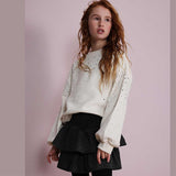 Gonna nera a balze con effetto lurex indossata da bambina con maglione chiaro decorato