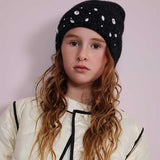 Cappellino nero lavorato a maglia con decorazioni brillanti indossato da bambina